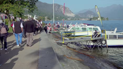 Passengers-start-boarding-a-sightseeing-boat-at-the-docking-point-in-the-port-of-Stresa,-Lake-Maggiore,-Piedmont,-Italy