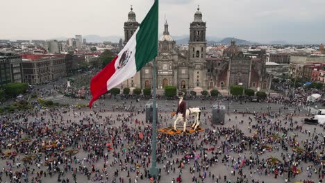 Mexico-City's-Zocalo,-its-iconic-cathedral,-mexican-flag-and-the-crowd-enjoying-day-of-the-dead-decoration