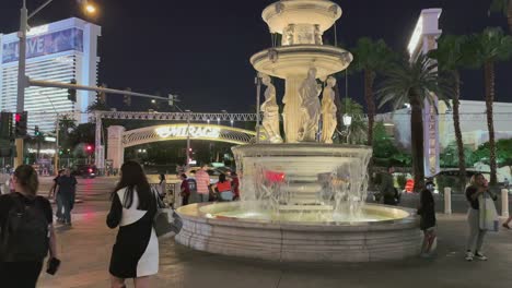 People-at-night-on-the-Strip-in-Las-Vegas-with-lit-fountain-and-cascading-water