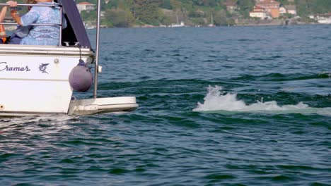 Stern-or-rear-of-a-boat-with-engine-running-and-passengers-waiting-for-it-to-leave-the-docking-point-at-Stresa-port-in-Piedmont,-Italy