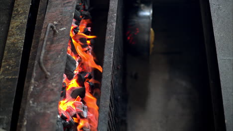 Dolly-in-shot-of-red-hot-burning-flaming-charcoal-in-an-old-rusted-restaurant-grill