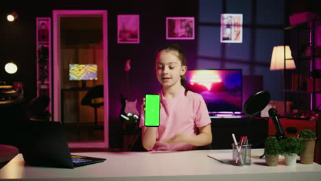 Child-media-star-showing-green-screen-smartphone-to-fans,-unpacking-it-and-presenting-specifications