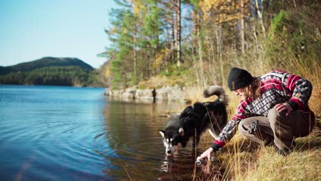 Alaskan-Malamute-Hund-Mit-Seinem-Besitzer-Am-See-In-Hildremsvatnet,-Norwegen---Breit