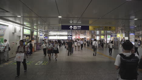Train-station-in-Tokyo,-Japan,-travel-transit-crowds-tourism-walking-people-busy