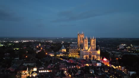 Aerial-drone-video-showcases-the-famous-Lincoln-Cathedral-in-Lincolnshire,-UK,-at-dusk,-emphasizing-its-illuminated-Gothic-architecture