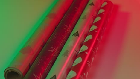 Christmas-wrapping-paper-rolls,-vibrant-red-green-two-light---medium-shot-slide-back-slow-motion