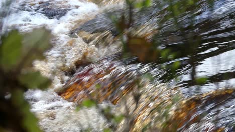 Peaceful-autumn-winter-woodland-setting,-a-meandering-stream-flows-over-rocks,-producing-small-waterfalls