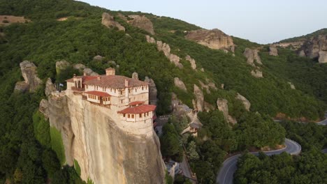 Meteora-Monasteries-in-Greece-at-sunset,-with-Landscape-scenery-and-green-hills,-Aerial-view