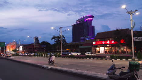 Tall-building-hotel-with-purple-lights-viewed-along-the-highway-under-a-cloudy-blue-sky