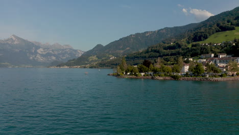 Forward-moving-shot-with-small-camping-ground-in-the-foreground,-revealing-a-mountain-lake-in-background-at-summer