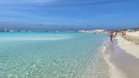 Amazing-summer-vacation-in-Formentera-island-Ses-Illetes-beach-Ibiza-Spain,-transparent-turquoise-water-on-a-white-sand-beach,-people-on-holiday,-sunny-day,-4K-static-shot