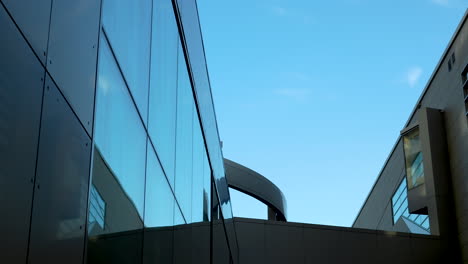 Glass-building-with-reflective-surface-and-clear-blue-sky