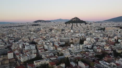Athens-Acropolis-and-Parthenon-at-sunset-with-city-skyline-in-the-horizon,-Aerial-view