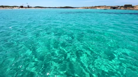 Magic-boat-ride-through-transparent-turquoise-water,-summer-dream-vacation-destination-in-Formentera-island-Ses-Illetes-beach-Ibiza-Spain,-4K-shot