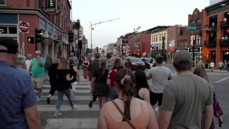 People-walking-along-Broadway-Street-in-Nashville,-Tennessee-in-slow-motion-with-gimbal-walking-behind