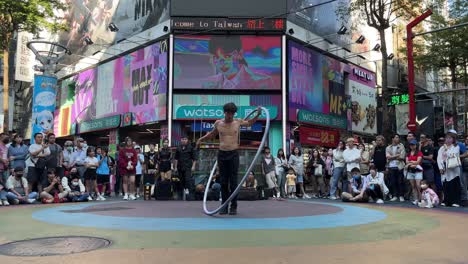 Tourists-watch-a-Taiwanese-male-busker-doing-street-performances-in-Ximending,-a-shopping-district-in-Taipei,-Taiwan