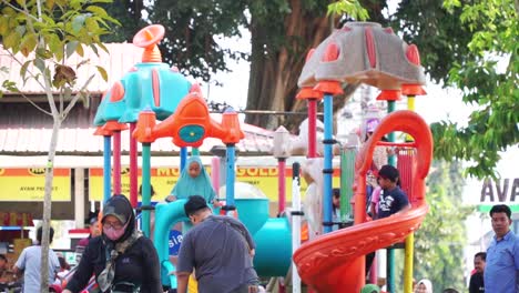 Slow-motion-shot-of-kids-and-parents-playing-in-playground-in-Indonesia,-Asia