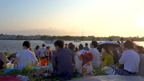 Menschenmenge-In-Japan-Im-Kimono,-Die-Bei-Sonnenuntergang-Am-Fluss-Sitzt
