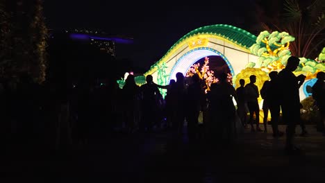 Silueta-De-Personas-En-Los-Jardines-Junto-A-La-Bahía-Festival-De-Mediados-De-Otoño-Exhibición-De-Linternas-Iluminadas-Por-La-Noche