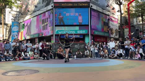 Tourists-watch-a-Taiwanese-female-busker-doing-street-performances-in-Ximending,-a-shopping-district-in-Taipei,-Taiwan