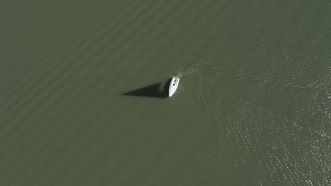 Drone-shot-of-a-sailboat-turning-around-in-a-lake