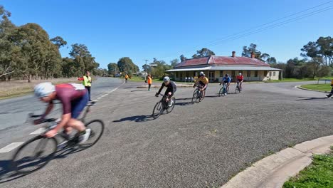 Wilby,-Victoria,-Australia---21-August-2022:-Road-race-cyclists-rounding-the-bend-in-the-township-of-Wilby,-Victoria,-Australia