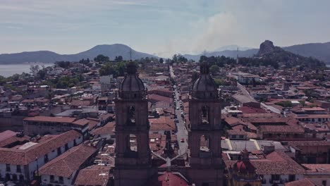 Drone's-rear-shot-passing-between-the-towers-of-the-Parish-of-San-Francisco-de-Asís-in-the-center-of-Valle-de-Bravo-on-a-sunny-day
