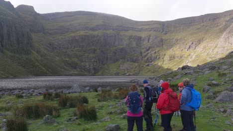 Mountain-guide-pointing-out-natural-features-to-a-group-of-hillwalkers-at-Coumshingaun-Lake-Comeragh-Mountains-Waterford-Ireland-in-winter-morning