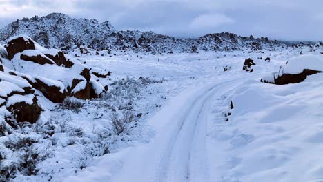 Cinematic-drone-shot-of-a-snow-covered-road-in-the-Alabama-Hills,-California