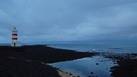 Pan-Desde-Un-Mar-Tranquilo-Hasta-Un-Antiguo-Faro-En-Un-Día-Temprano-En-Islandia