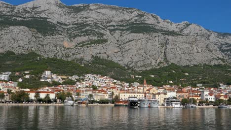 Panorama-of-Mediterranean-seaside-town-by-dramatic-mountains,-Makarska,-Croatia