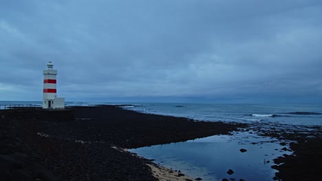 Pan-Desde-Un-Antiguo-Faro-Hasta-Un-Mar-En-Calma-En-Gardur,-Islandia