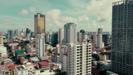 drone-view-panning-left-looking-over-the-high-rise-buildings-in-the-city-of-Phnom-Penh,-Cambodia