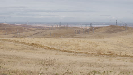 Wide-shot-of-windmills-on-dry-hills-on-a-cloudy-day