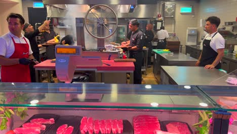 Cocina-Abierta-Y-Tienda-De-Carne-En-Un-Restaurante-Con-Carne-Cruda-Fresca-Y-Mucha-Gente-Trabajando-Y-Cocinando,-Carnicería,-Toma-De-4k