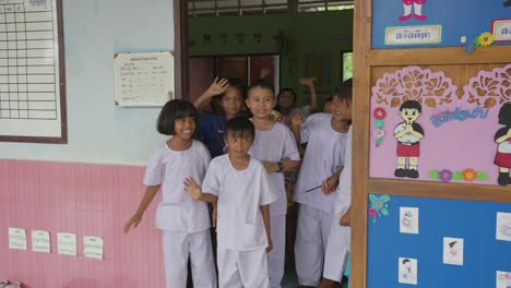 Thailändische-Kinder-Verabschieden-Sich-Liebevoll-Mit-Winken,-Ihr-Lächeln-Spiegelt-Die-Wärme-Gemeinsamer-Momente-Und-Abschiede-An-Der-Tür-Wider