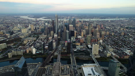 Elevated-shot-backwards-over-the-cityscape-of-Philadelphia,-autumn-dusk---Aerial-view