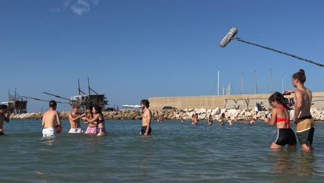 Personas-Que-Trabajan-En-Un-Equipo-De-Filmación-Sumergidos-En-Agua-De-Mar-Filman-Escenas-De-Niños-Y-Niñas-Jugando-En-La-Temporada-De-Verano-Para-La-Producción-De-Películas-O-Series-De-Televisión