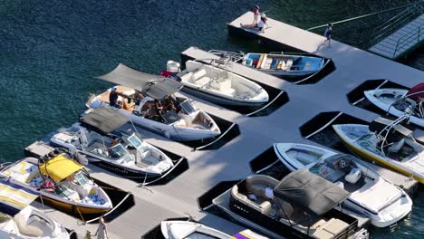 multiple-boats-docked-on-Lake-Arrowhead-with-people-walking-down-the-floating-boardwalk-AERIAL-TELEPHOTO-STATIC