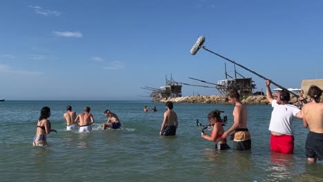 Personas-Que-Trabajan-En-Un-Equipo-De-Filmación-Inmersos-En-Agua-De-Mar-Filman-Escenas-De-Niños-Y-Niñas-Jugando-En-La-Temporada-De-Verano-Para-La-Producción-De-Películas-O-Series-De-Televisión