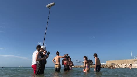 Filmtruppe-Badet-Im-Meerwasser-Und-Filmt-Szenen-Von-Jungen-Und-Mädchen,-Die-In-Der-Sommersaison-Für-Die-Produktion-Von-Filmen-Oder-Fernsehserien-Spielen