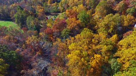 A-high-angle,-aerial-view-high-up-over-a-quiet-country-road-with-colorful-trees-on-a-sunny-day-in-autumn