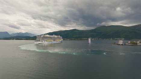 Cruise-liner-arrives-off-Ålesund-port-town-in-Norway,-aerial-arc-shot