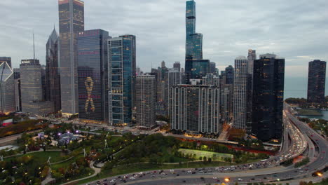 Aerial-view-toward-the-illuminated-Maggie-Daley-park-and-skyscrapers,-fall-in-New-Eastside,-Chicago