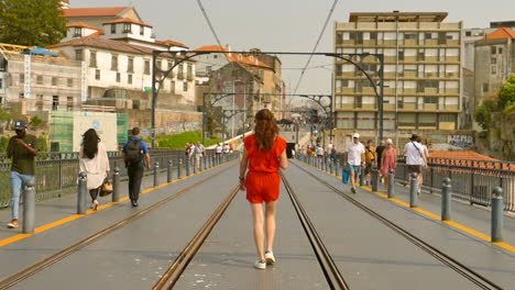 Folgende-Aufnahme-Einer-Frau,-Die-Morgens-Auf-Der-Obersten-Ebene-Der-Dom-Luís-i-Brücke-Geht,-Wo-Die-U-Bahn-In-Porto,-Portugal,-Vorbeifährt