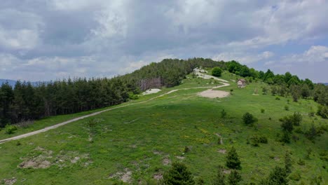 Aerial-approaching-shot-of-trail-on-hill-to-summit-during-cloudy-day-in-Bulgaria