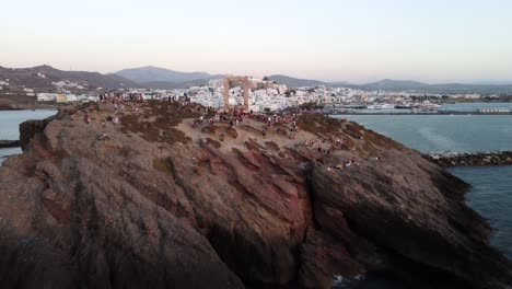 Turistas-Disfrutando-De-La-Puesta-De-Sol-En-El-Templo-De-Apolo-De-La-Isla-De-Naxos,-Grecia,-Vista-Aérea