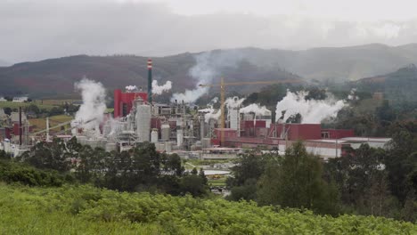 Eine-Papierindustrie,-Die-Aus-Vielen-Schornsteinen-In-Einer-Grünen-Ländlichen-Gegend-Rauch-Und-Schadstoffe-Ausstößt,-Während-Der-Wind-An-Einem-Bewölkten-Tag-Die-Verschmutzung-Verteilt