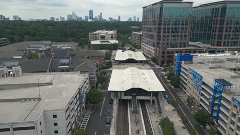 Aerial-flyover-Lindbergh-Marta-Station-and-park-trees-with-Skyline-of-Buckhead-Atlanta-in-background,-USA