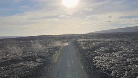 Atemberaubende-Luftaufnahme-Eines-Autos,-Das-In-Den-Feurigen-Sonnenuntergang-über-Einem-Vulkanischen-Lavafeld-Auf-Big-Island,-Hawaii,-Fährt
